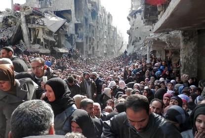 Masses of refugees wait in line to receive food aid 